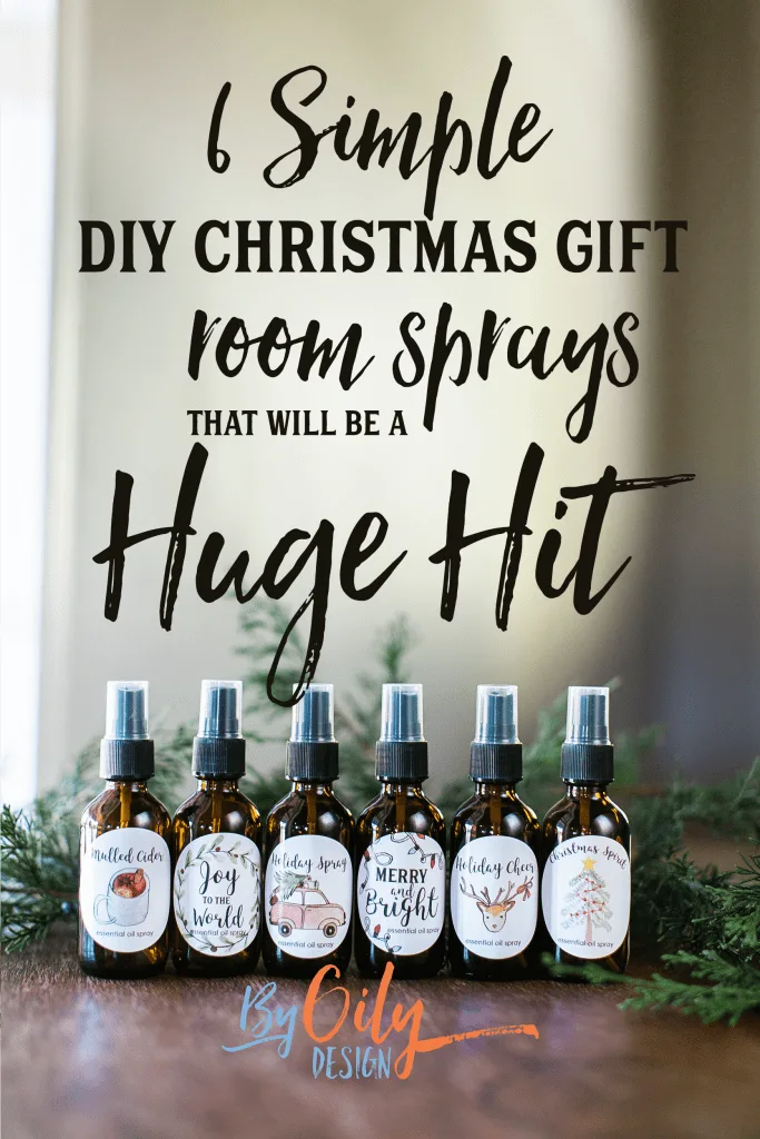 6 Essential Oil room spray bottles on a wood table with varying Christmas labels and evergreen branches.