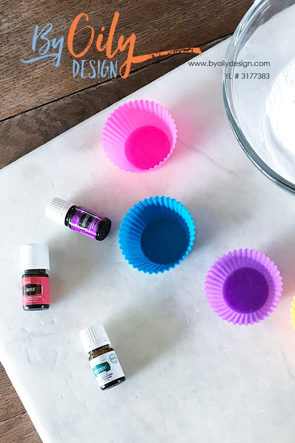 Essential oils, silicone molds and baking soda laid out on a table to ready to make shower steamers.