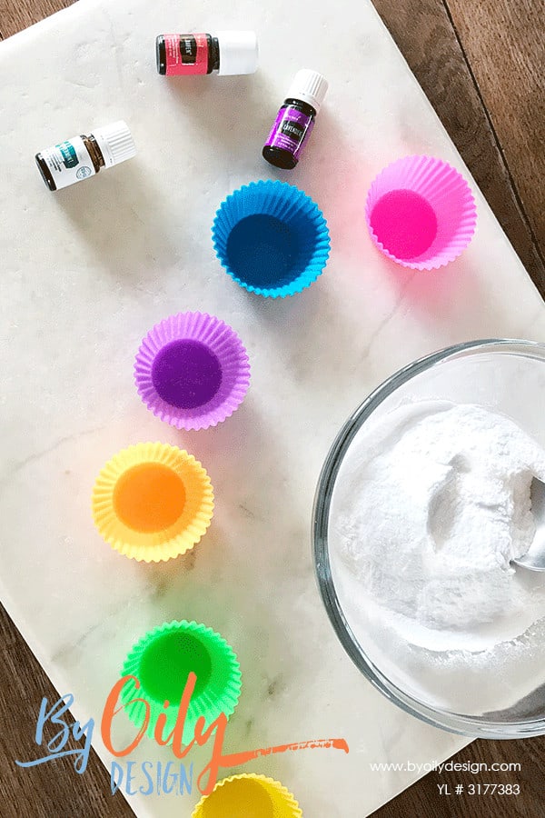 Essential oils, silicone molds and baking soda laid out on a table to ready to make shower steamers.