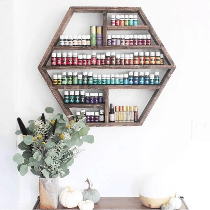 Large wooden hexagon shelf holding bottles of essential oils