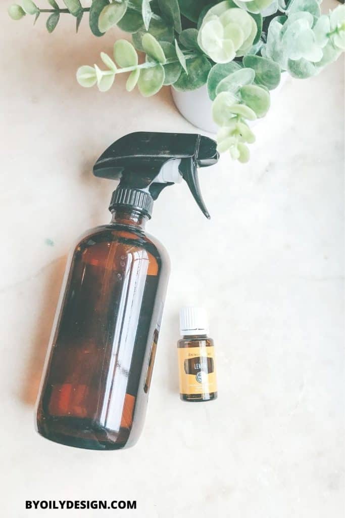 homemade glass cleaner in an amber spray bottle with lemon oil next to it.