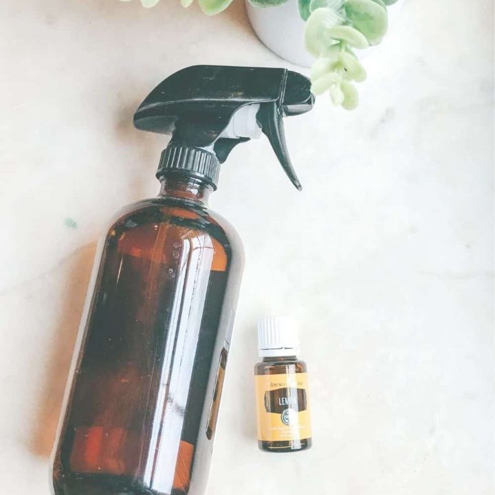 homemade glass cleaner in a amber spray bottle with lemon oil next to it.