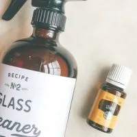 bottle of homemade glass cleaner next to a bottle of lemon essential oil
