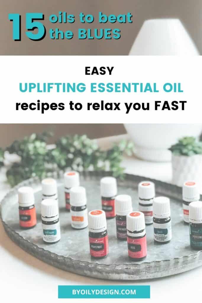 15 uplifting essential oils spaced out on metal tray in front of a diffuser with greenery