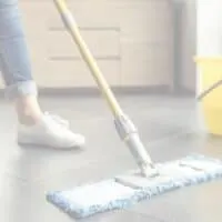 woman using all natural homemade floor cleaner to mop her tile floor.