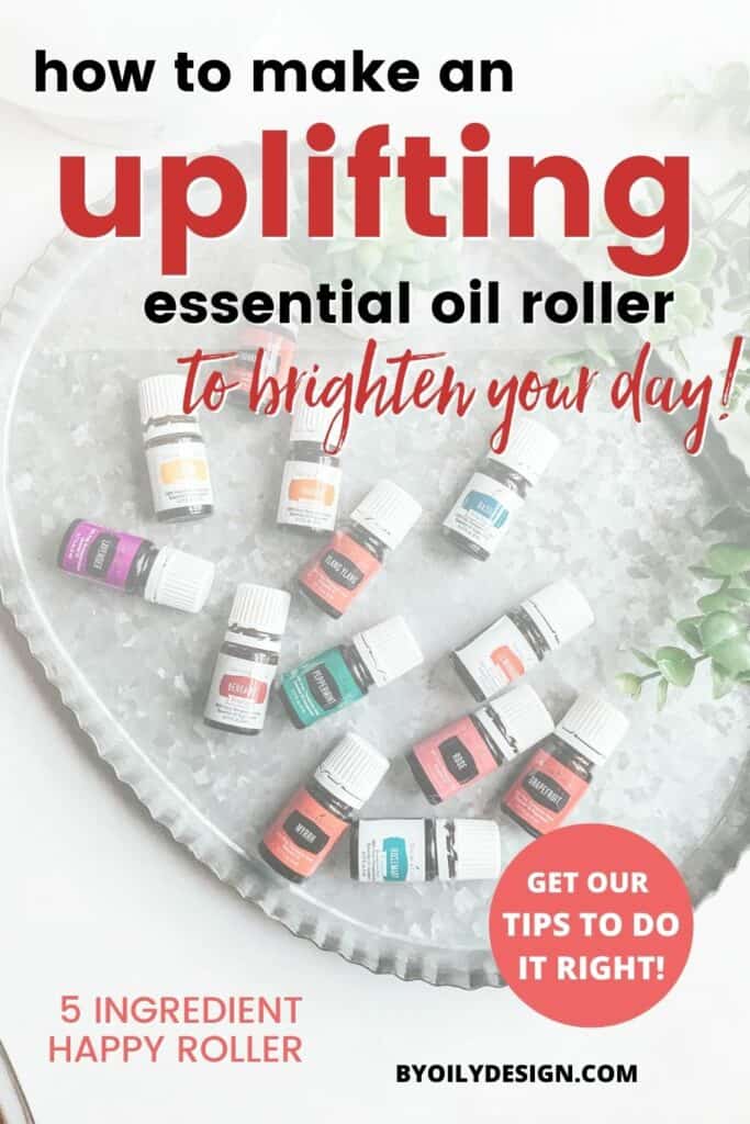 image of 14 uplifting essential oils known to boost your mood. The oils are laying on a silver metal pan on top of a white surface. Text on the image says "how to make an uplifting oil roller to brighten your day".