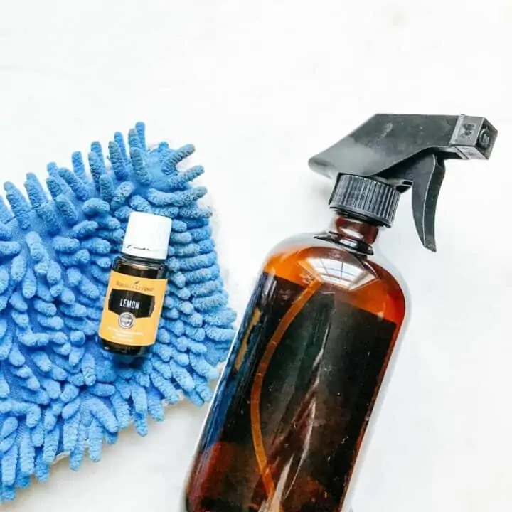 Lemon essential oil, mop and spray bottle showing tools to make homemade laminate floor cleaner.