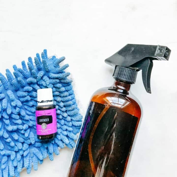 Lavender oil on top of a mop head next to a amber spray bottle. Showing tools used for making homemade tile floor cleaner.